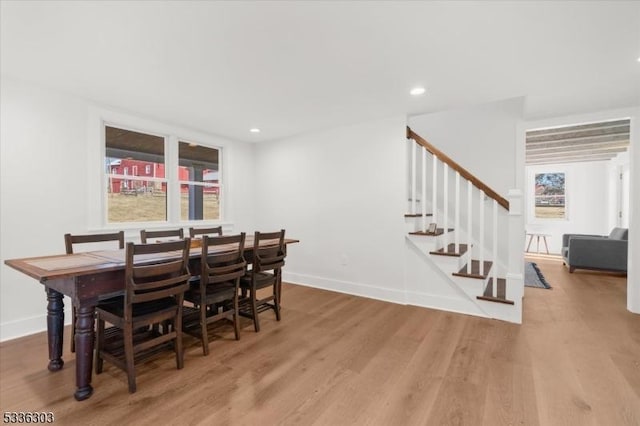 dining space featuring stairway, light wood-type flooring, and baseboards