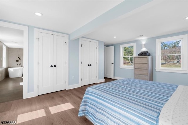 bedroom featuring recessed lighting, wood finished floors, baseboards, and multiple closets