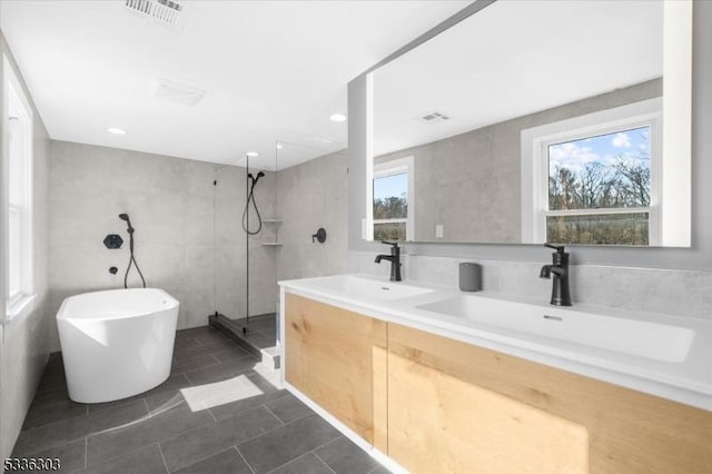 full bathroom with a sink, visible vents, walk in shower, and a freestanding tub