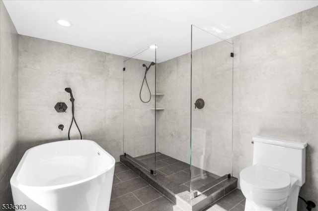 bathroom with tile walls, tile patterned floors, a shower stall, and a freestanding bath