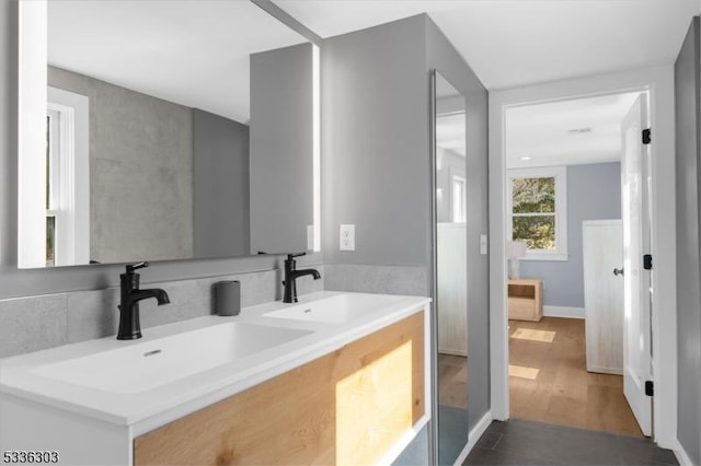 bathroom with double vanity, wood finished floors, and a sink