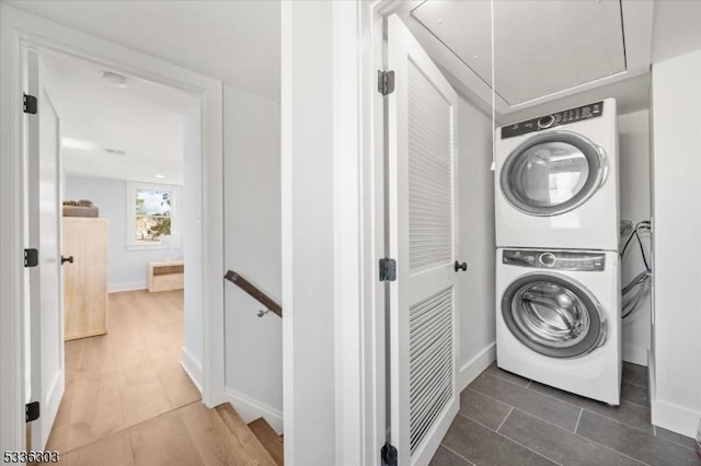 laundry area with baseboards, attic access, laundry area, stacked washer / drying machine, and tile patterned floors