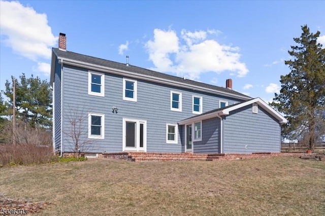 rear view of property featuring a yard and a chimney