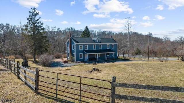 view of front of home with a fenced front yard, a chimney, covered porch, and a front yard