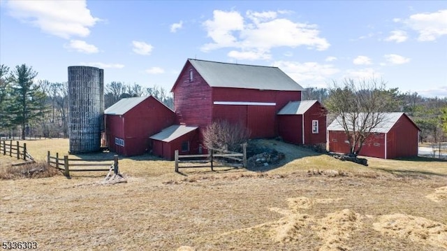 view of side of property with a barn, an outdoor structure, and fence