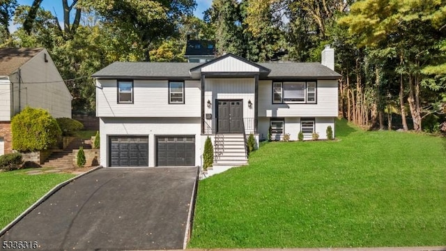 raised ranch featuring a garage and a front lawn