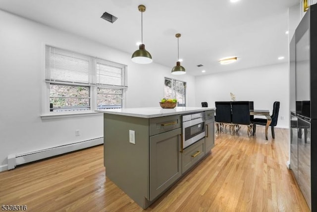 kitchen with a kitchen island, pendant lighting, a baseboard heating unit, stainless steel refrigerator with ice dispenser, and light hardwood / wood-style flooring