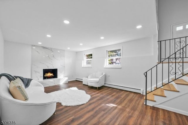 living room featuring a high end fireplace, dark hardwood / wood-style flooring, and a baseboard heating unit