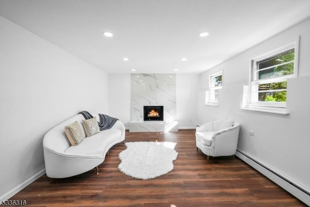 living area featuring a baseboard radiator, a high end fireplace, and dark hardwood / wood-style flooring