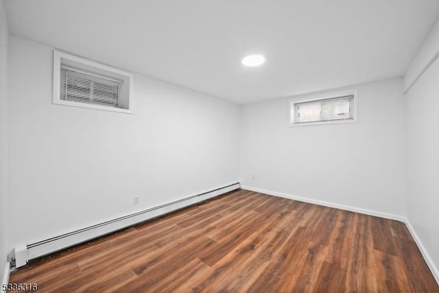 basement with a baseboard heating unit and dark hardwood / wood-style floors