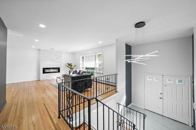 foyer featuring wood-type flooring, a notable chandelier, and a fireplace