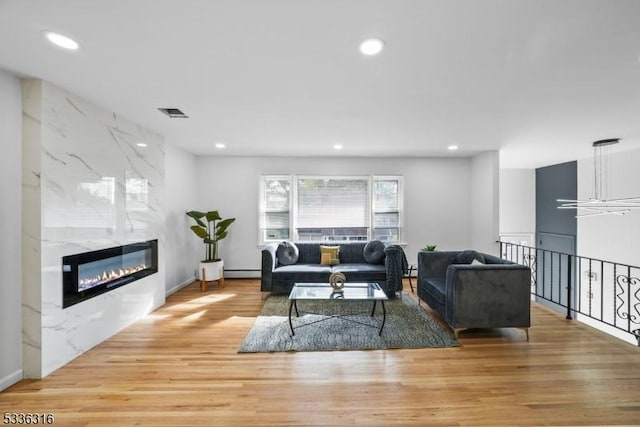 living room with a high end fireplace, hardwood / wood-style floors, and a baseboard heating unit