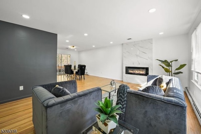 living room featuring a baseboard radiator, a premium fireplace, and light wood-type flooring