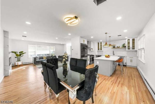 dining area with light hardwood / wood-style flooring, sink, and a baseboard radiator