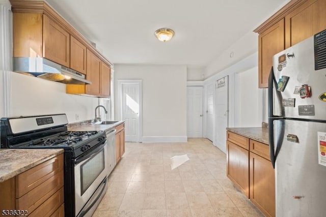 kitchen with stainless steel appliances, light stone countertops, and sink