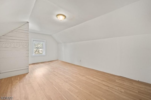 additional living space with vaulted ceiling and light hardwood / wood-style floors