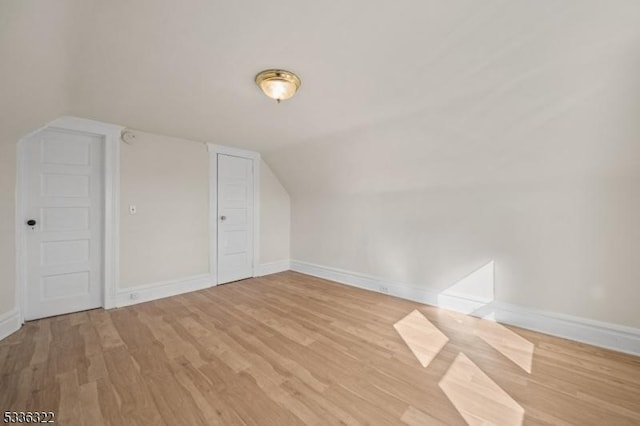 bonus room with vaulted ceiling and light wood-type flooring