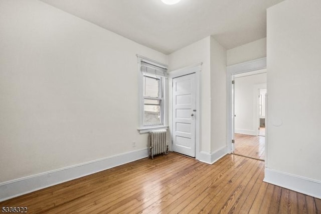 unfurnished bedroom featuring radiator heating unit and light wood-type flooring