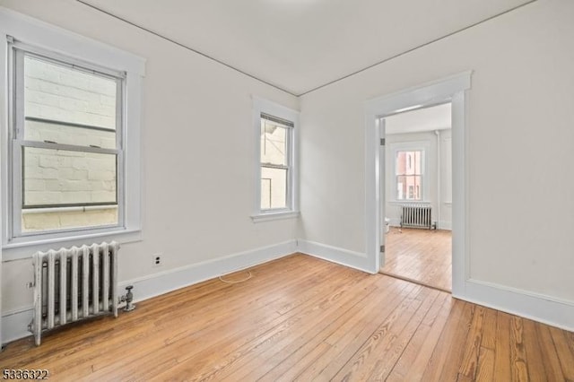 unfurnished room with radiator and light wood-type flooring