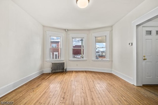 spare room featuring radiator heating unit and light hardwood / wood-style floors