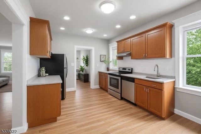 kitchen featuring appliances with stainless steel finishes, sink, light hardwood / wood-style floors, and decorative backsplash