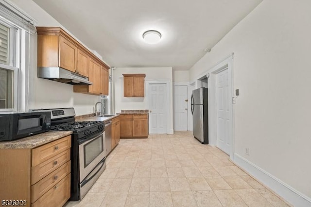 kitchen with light stone counters, sink, and stainless steel appliances