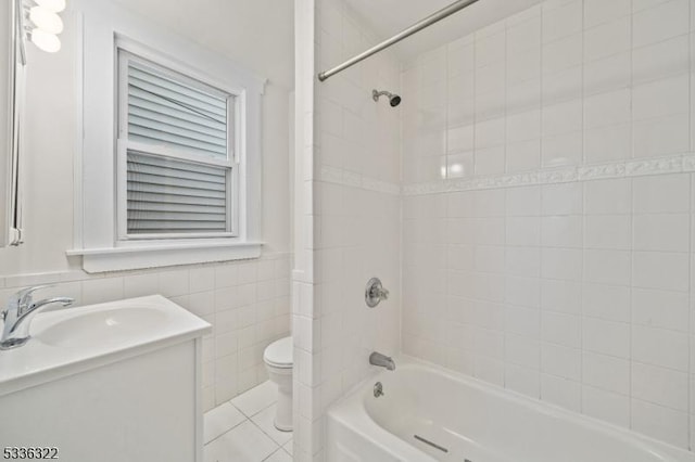 full bathroom featuring tile patterned flooring, tile walls, vanity, toilet, and tiled shower / bath