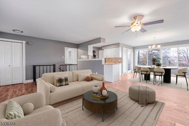 living room featuring ceiling fan with notable chandelier and light hardwood / wood-style floors