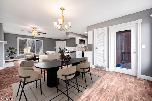 dining area featuring ceiling fan with notable chandelier and light hardwood / wood-style floors