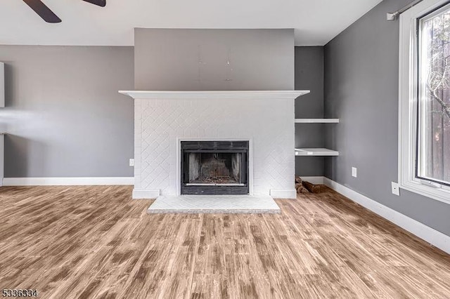 unfurnished living room featuring hardwood / wood-style flooring, a fireplace, and ceiling fan