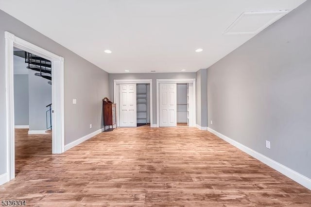 unfurnished bedroom featuring multiple closets and light hardwood / wood-style floors