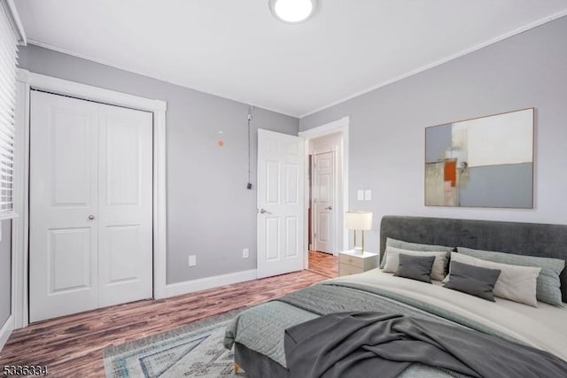 bedroom with hardwood / wood-style flooring, ornamental molding, and a closet