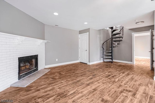 unfurnished living room featuring hardwood / wood-style flooring and a brick fireplace