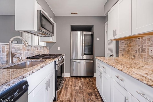 kitchen with light stone counters, white cabinets, and appliances with stainless steel finishes