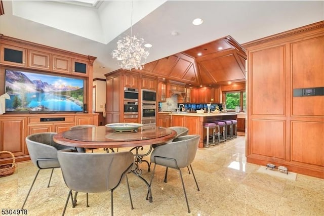 dining room featuring a towering ceiling, sink, and an inviting chandelier