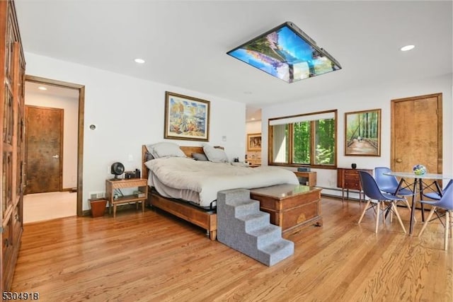 bedroom with a baseboard heating unit and light hardwood / wood-style flooring