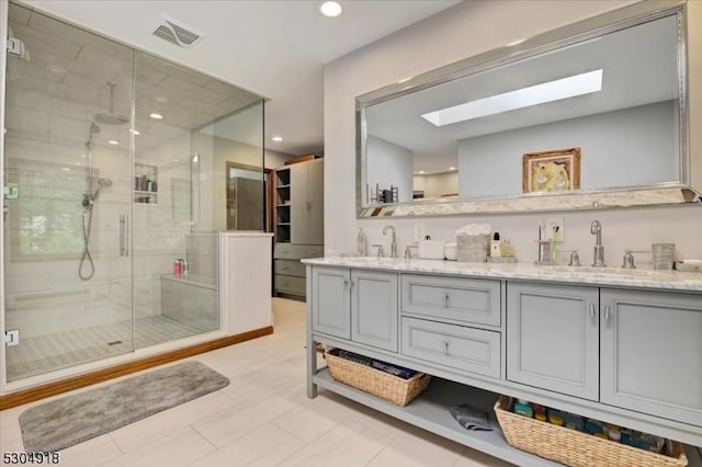 bathroom featuring vanity, a skylight, and a shower with door