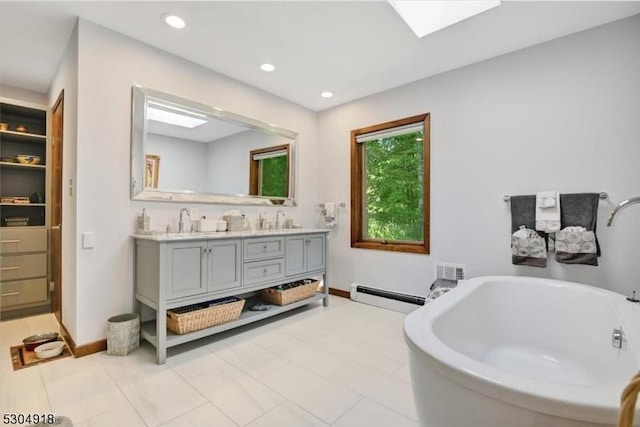 bathroom featuring vanity, a skylight, a washtub, and a baseboard heating unit