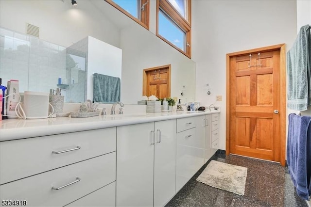 bathroom featuring vanity, a shower, and a towering ceiling