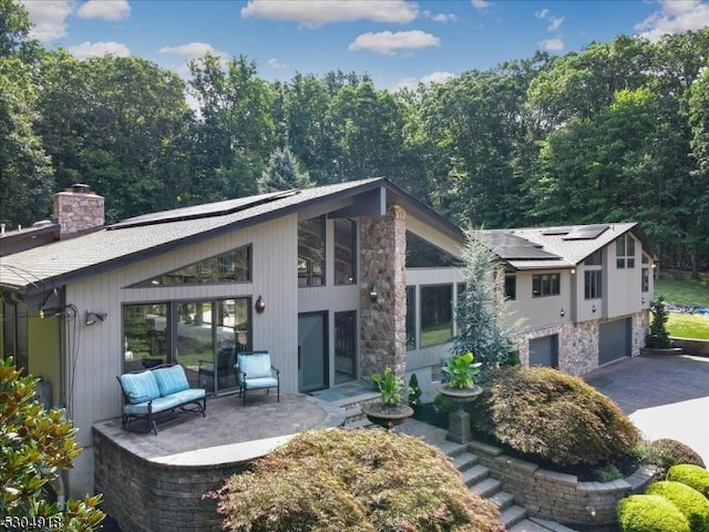 back of property featuring a garage and solar panels