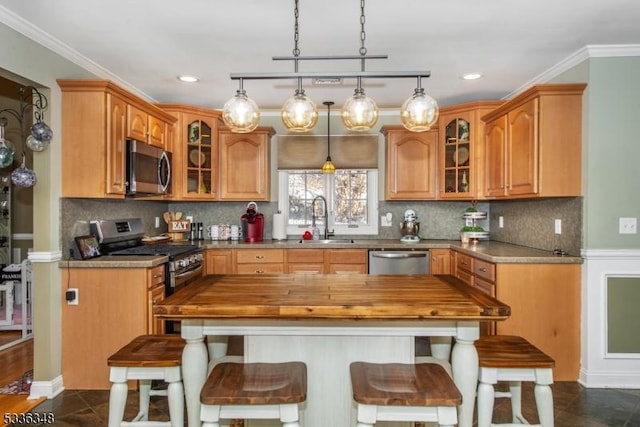 kitchen featuring hanging light fixtures, ornamental molding, appliances with stainless steel finishes, and sink