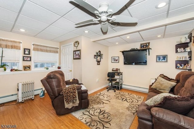 living room with ceiling fan, a drop ceiling, light hardwood / wood-style floors, and baseboard heating