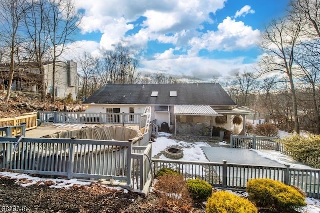 snow covered house featuring a wooden deck and an outdoor fire pit