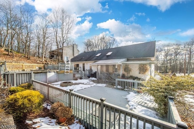 snow covered back of property featuring a deck