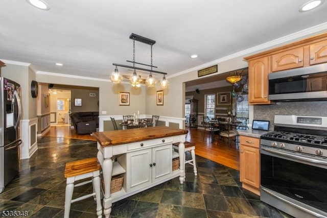 kitchen with crown molding, decorative light fixtures, light brown cabinets, and appliances with stainless steel finishes