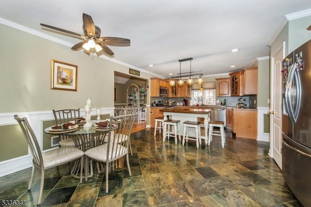 dining area featuring sink, ornamental molding, and ceiling fan