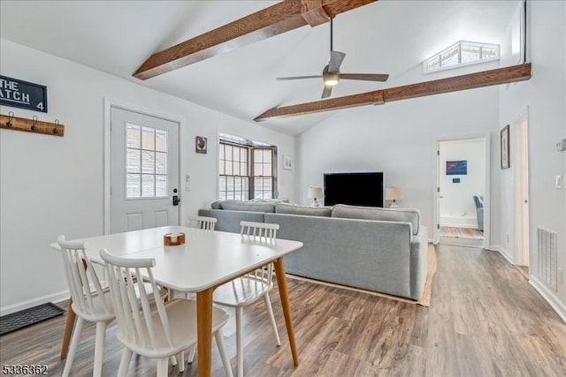 dining space with ceiling fan, high vaulted ceiling, beam ceiling, and light hardwood / wood-style flooring