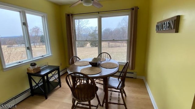 dining room with light wood-type flooring, baseboard heating, and ceiling fan