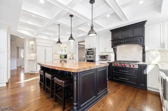 kitchen with dark wood finished floors, appliances with stainless steel finishes, white cabinetry, a kitchen island, and a kitchen breakfast bar