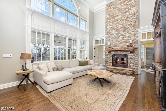 living area featuring baseboards, a fireplace, dark wood finished floors, and crown molding